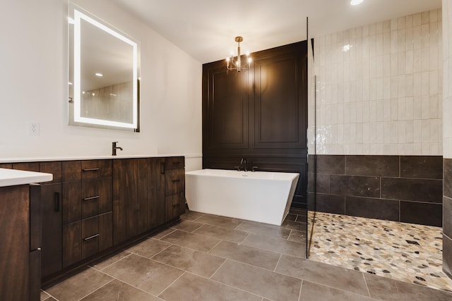 bathroom with an inviting chandelier, tile patterned floors, shower with separate bathtub, vanity, and tile walls