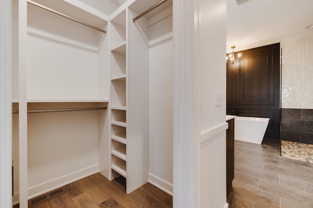 spacious closet with a chandelier and light hardwood / wood-style floors