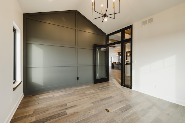 spare room with a chandelier, high vaulted ceiling, and light hardwood / wood-style flooring