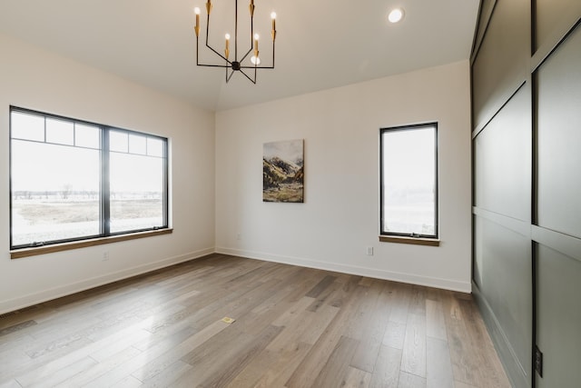 unfurnished room with light hardwood / wood-style floors and an inviting chandelier