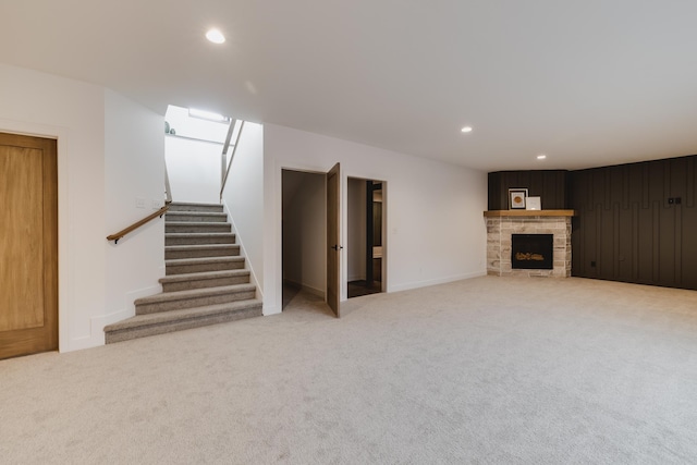 unfurnished living room with a stone fireplace and light carpet