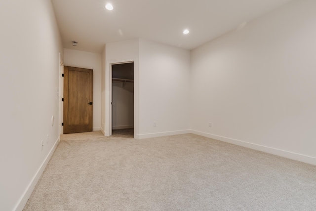 unfurnished bedroom featuring a walk in closet and light colored carpet