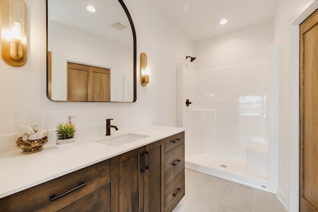 bathroom with tile patterned flooring, vanity, and walk in shower