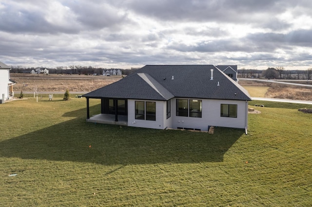 back of property featuring a yard and a rural view