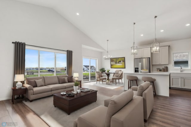 living room featuring a notable chandelier, light hardwood / wood-style flooring, high vaulted ceiling, and sink