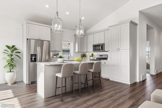 kitchen featuring a kitchen island, appliances with stainless steel finishes, hanging light fixtures, and a kitchen bar