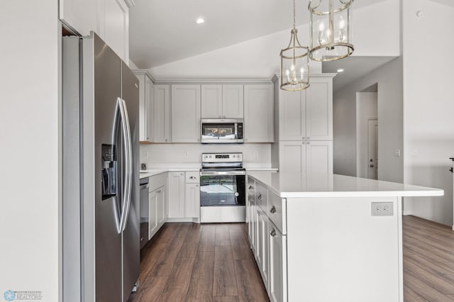 kitchen with appliances with stainless steel finishes, decorative light fixtures, lofted ceiling, a center island, and dark wood-type flooring