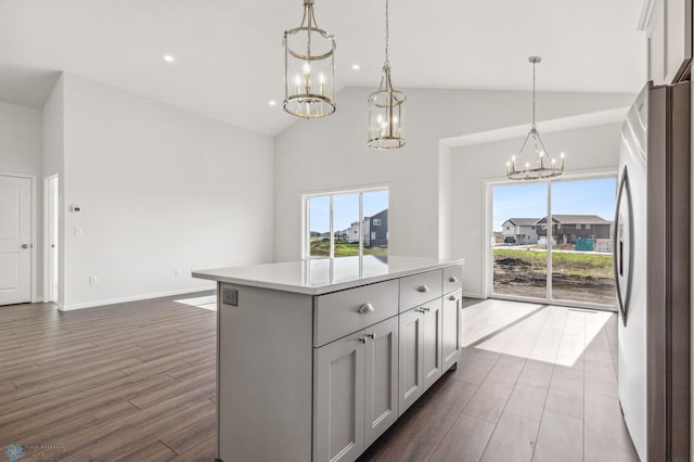 kitchen with a kitchen island, a healthy amount of sunlight, pendant lighting, and stainless steel fridge