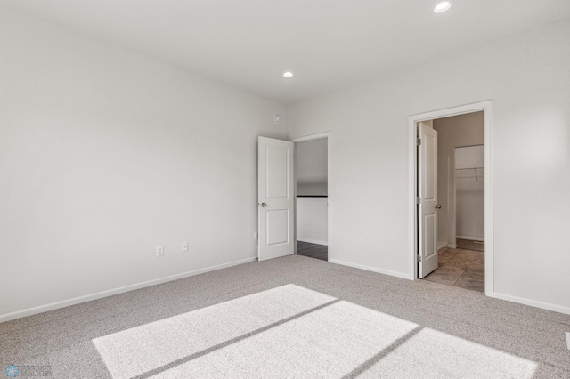 unfurnished bedroom with a spacious closet and light colored carpet