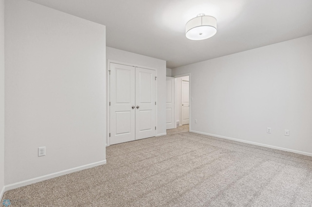 unfurnished bedroom featuring light colored carpet and a closet