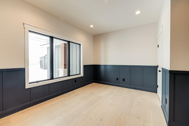 empty room with recessed lighting, wainscoting, visible vents, and light wood finished floors