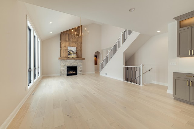 unfurnished living room featuring high vaulted ceiling, light wood finished floors, a fireplace, and baseboards