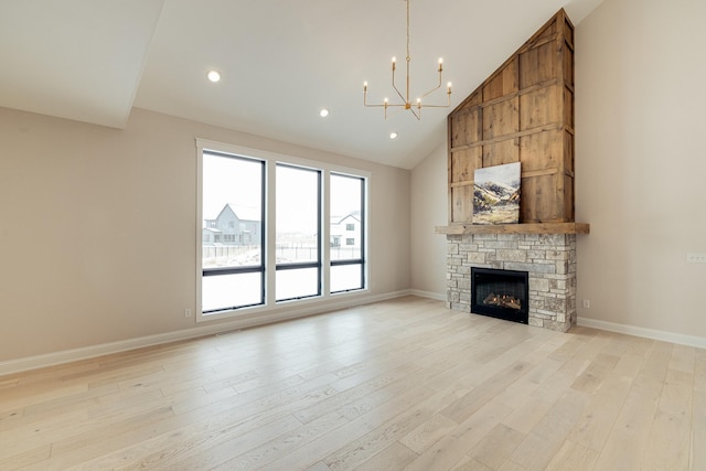 unfurnished living room with baseboards, an inviting chandelier, a stone fireplace, light wood-style floors, and high vaulted ceiling