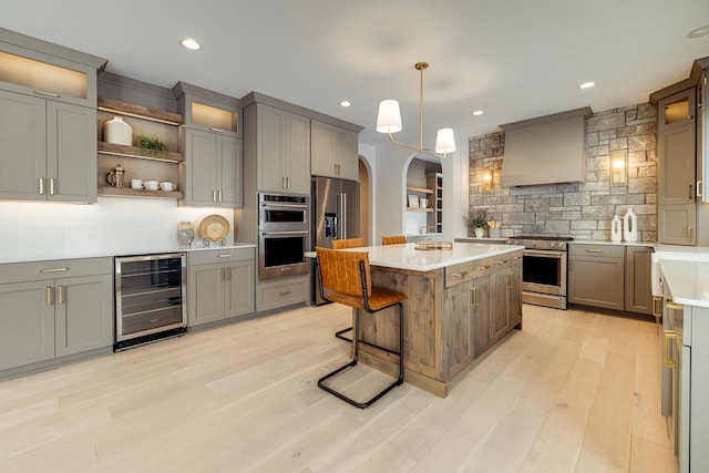 kitchen featuring custom range hood, a kitchen island, appliances with stainless steel finishes, light countertops, and open shelves