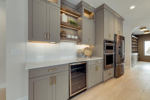 kitchen with beverage cooler, stainless steel appliances, light countertops, and gray cabinetry