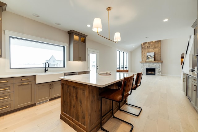 kitchen featuring open floor plan, a center island, hanging light fixtures, light countertops, and a sink