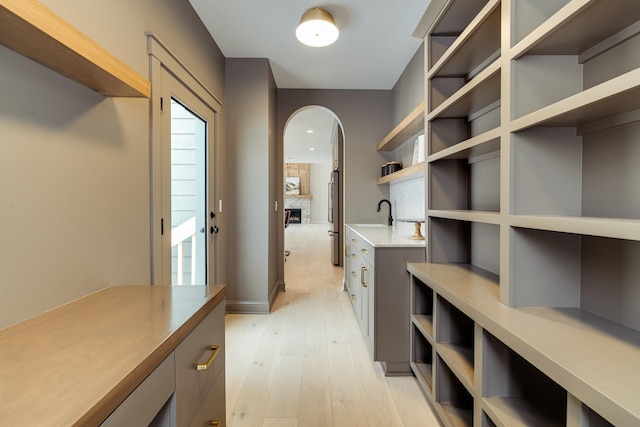 mudroom featuring light wood-style floors, a fireplace, and a sink