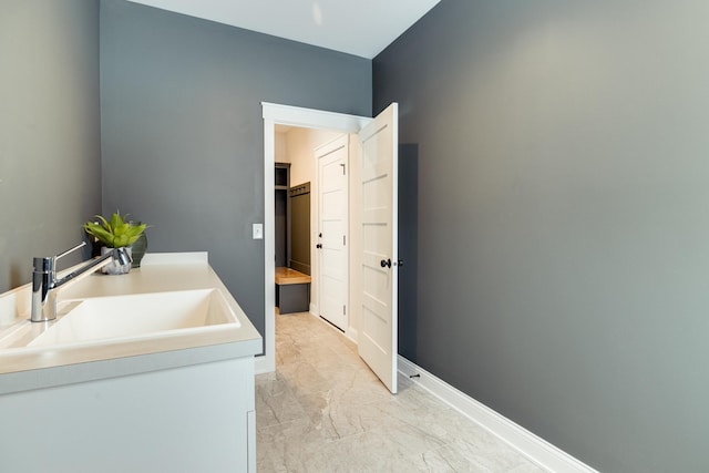 bathroom featuring marble finish floor, a sink, and baseboards