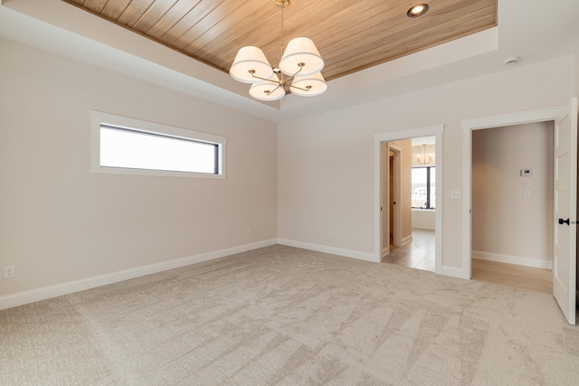 spare room with light carpet, wooden ceiling, a tray ceiling, and an inviting chandelier