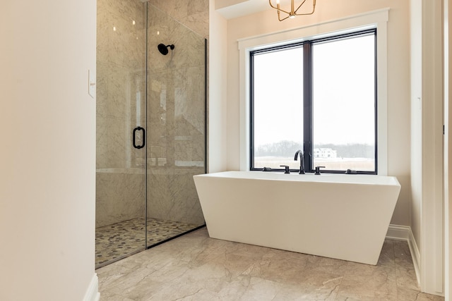 bathroom featuring marble finish floor, baseboards, a tile shower, and a freestanding bath