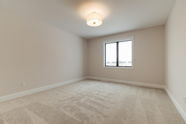 empty room featuring light carpet and baseboards