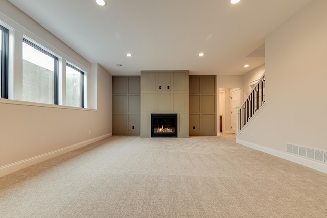 unfurnished living room featuring baseboards, visible vents, light colored carpet, and recessed lighting