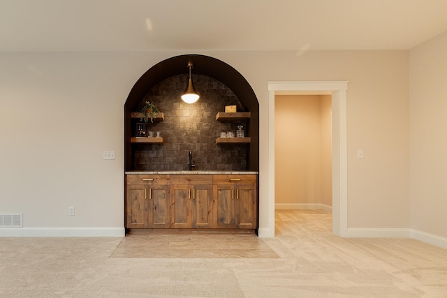 bar featuring indoor wet bar, light carpet, visible vents, and baseboards