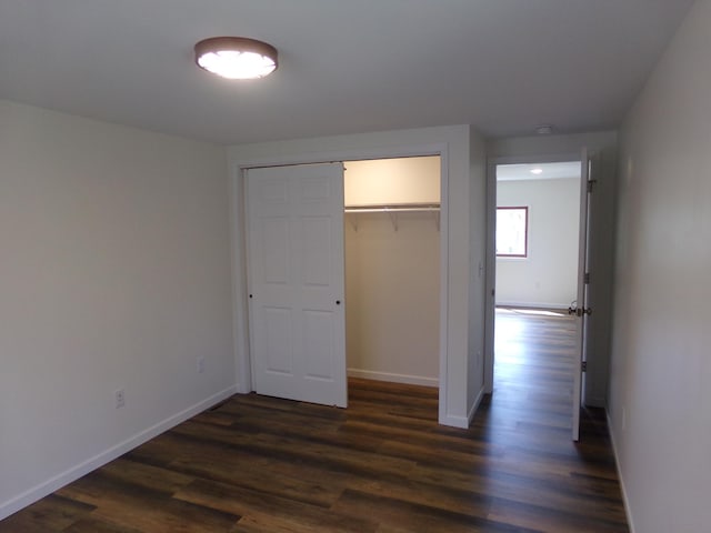 unfurnished bedroom with dark wood-type flooring, a closet, and a spacious closet