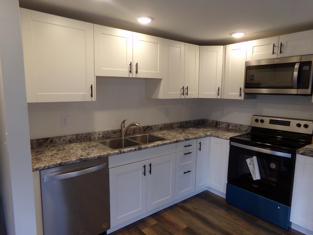 kitchen featuring stainless steel appliances, stone counters, dark hardwood / wood-style flooring, sink, and white cabinets