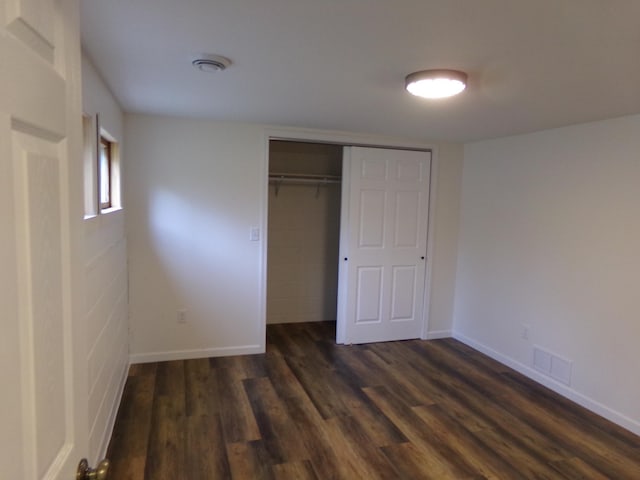 unfurnished bedroom with dark hardwood / wood-style floors and a closet