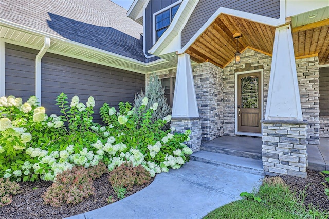 doorway to property with stone siding and roof with shingles