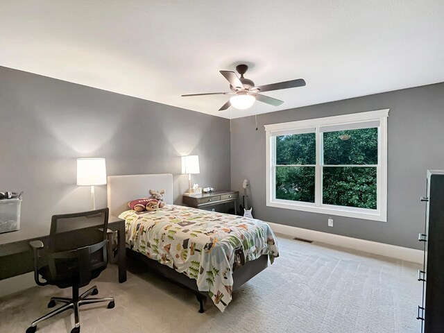 bedroom with light carpet, ceiling fan, visible vents, and baseboards