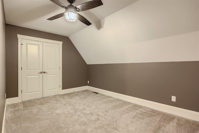 bonus room featuring light carpet, vaulted ceiling, a ceiling fan, and baseboards