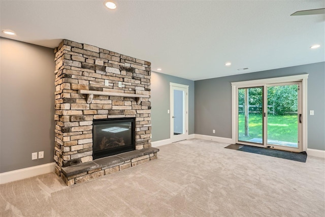 unfurnished living room featuring carpet floors, recessed lighting, baseboards, and a stone fireplace