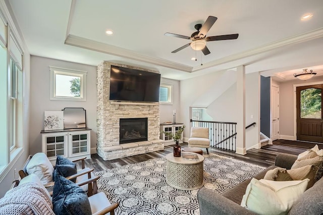 living area with dark wood-type flooring, a tray ceiling, ornamental molding, and baseboards