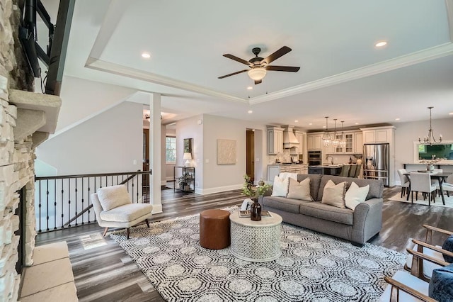 living room featuring baseboards, wood finished floors, a raised ceiling, and crown molding