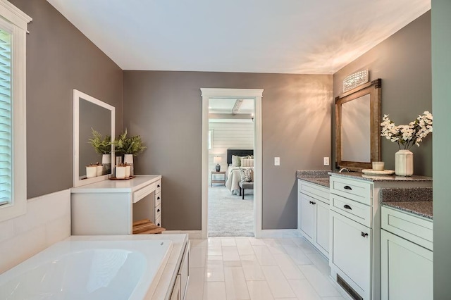 ensuite bathroom featuring baseboards, ensuite bathroom, a bath, and vanity