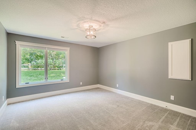 unfurnished room with a textured ceiling, carpet flooring, visible vents, and baseboards