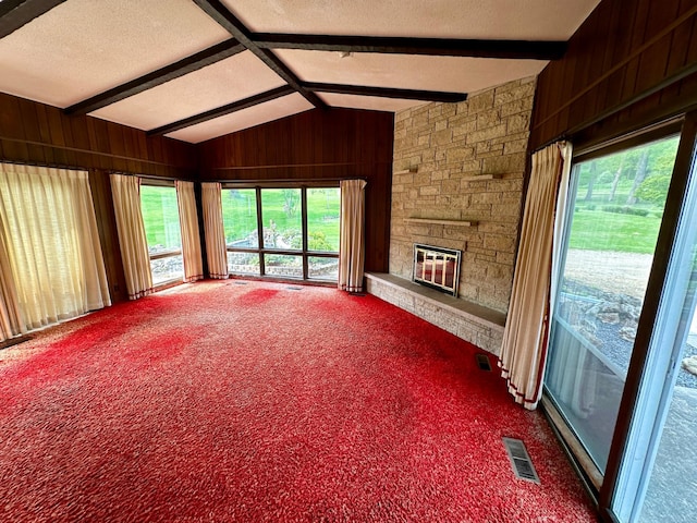 unfurnished living room featuring carpet flooring, a fireplace, wood walls, and lofted ceiling with beams