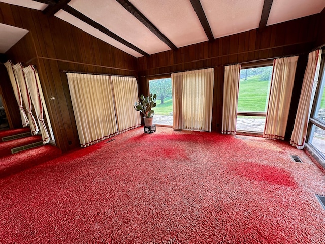 spare room with carpet, a healthy amount of sunlight, and vaulted ceiling with beams