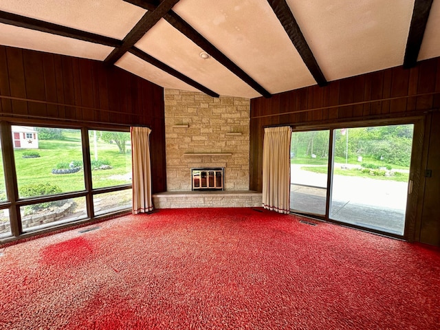 unfurnished living room with wooden walls, lofted ceiling with beams, a fireplace, and carpet