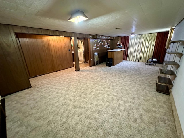 basement featuring carpet flooring and wood walls