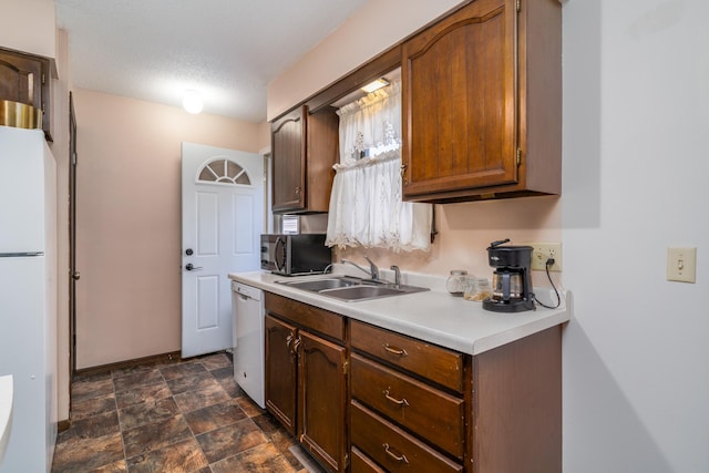 kitchen featuring a textured ceiling, white appliances, and sink