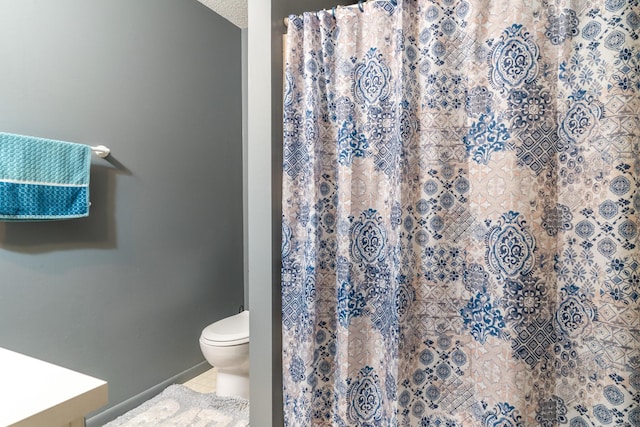 bathroom featuring curtained shower, tile patterned flooring, vanity, and toilet