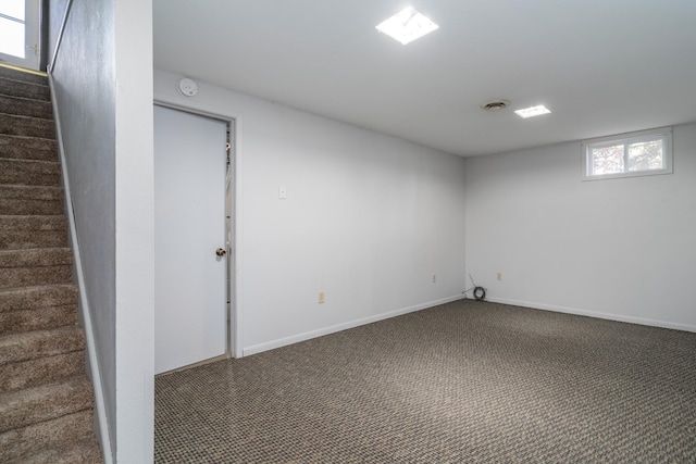 basement featuring dark colored carpet and a healthy amount of sunlight