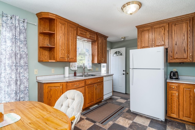 kitchen with a textured ceiling, white appliances, and sink