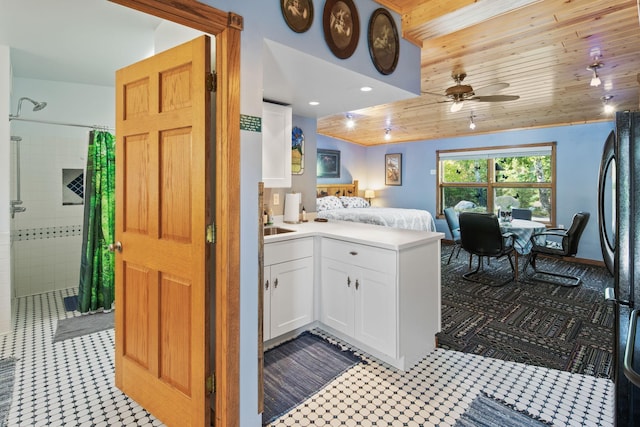 kitchen with ceiling fan, white cabinets, and wooden ceiling