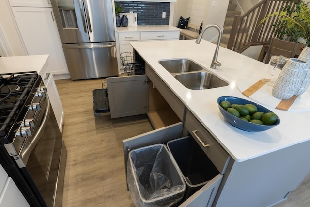 kitchen with decorative backsplash, stainless steel appliances, sink, light hardwood / wood-style floors, and white cabinetry