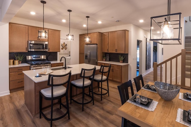 kitchen with tasteful backsplash, stainless steel appliances, dark hardwood / wood-style flooring, sink, and a kitchen island with sink