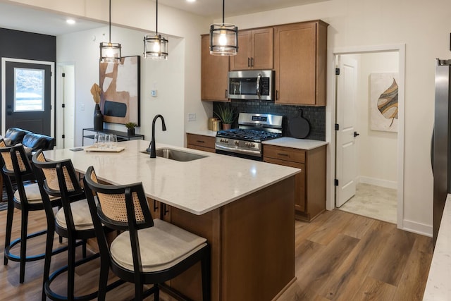 kitchen with stainless steel appliances, pendant lighting, backsplash, sink, and hardwood / wood-style flooring